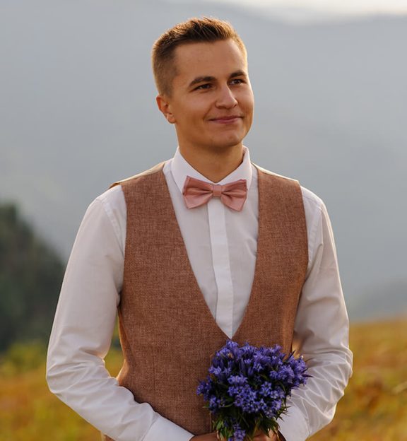 a-groom-with-a-bouquet-of-wildflowers-looks-at-his-2021-09-01-15-25-57-utc.jpeg